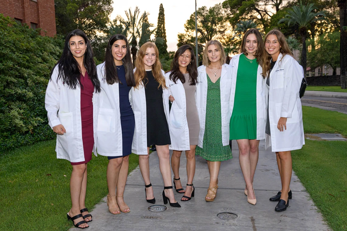 (From left) Sahar Davoudi, Lily Younan, Madisyn Kaus-Peru, Shannon Yee, Marisa Cannon, Sabine Obagi and Katharine Johnson pause for a photo on their way out of Centennial Hall after the College of Medicine – Tucson Class of 2026 white coat ceremony.