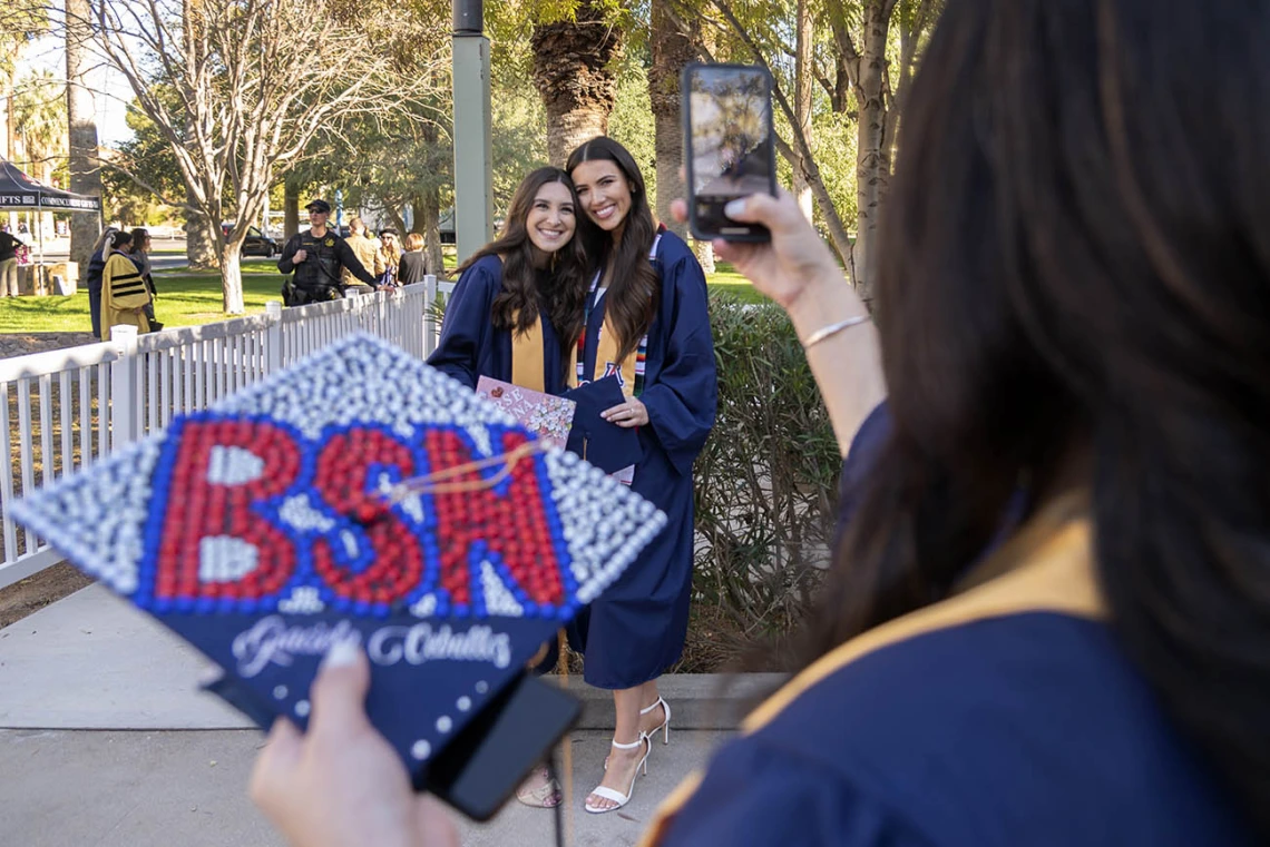 Graciela Ceballos takes a photo of her friends, Gianna Casella and Talia Acereto before the College of Nursing convocation at Centennial Hall.