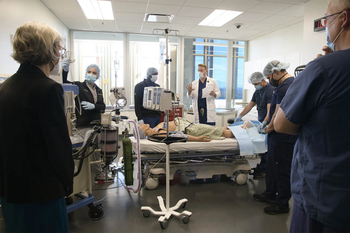 College of Nursing Dean Ki Moore, PhD, (left) listens as C. “Reggie” Elam, PhD, DNAP, CRNA, clinical assistant professor (white coat center), reviews how the CRNA students did in their first simulation of the day. 