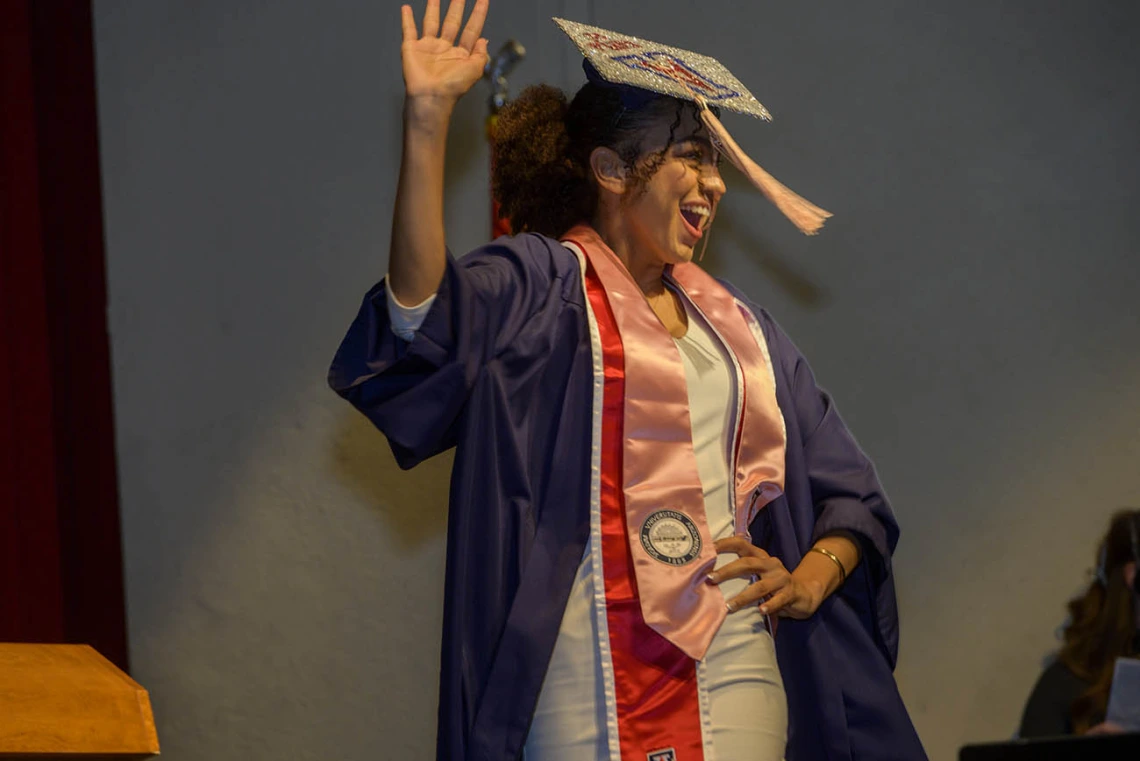 Kayla Allender hams it up for the audience as she walks onto the stage at Centennial Hall to receive her diploma during the Mel and Enid Zuckerman College of Public Health fall convocation. 