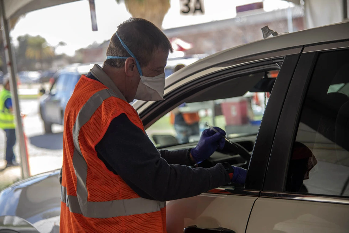 College of Pharmacy professor Michael Katz, PharmD, prepares to administer a COVID-19 vaccine to a patient at the Pima County drive-through POD at the University of Arizona.