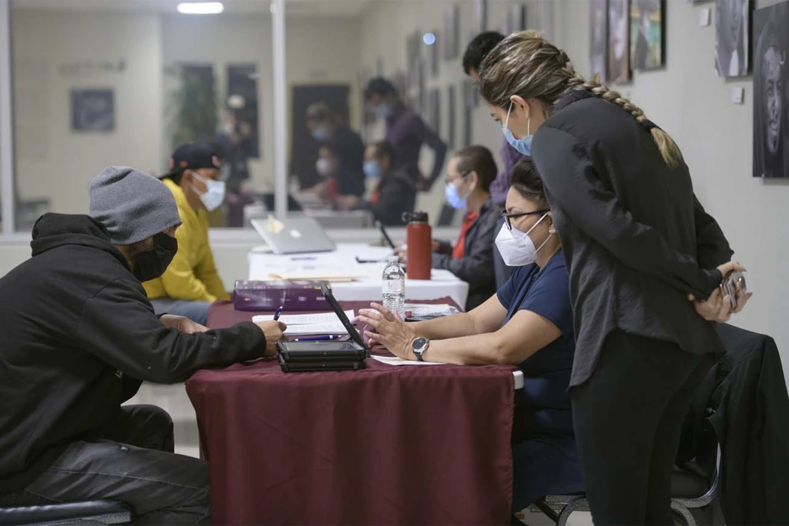 Intake staff at a COVID-19 vaccine clinic hosted by UArizona Health Sciences in the early morning hours of April 23 at the Mexican Consulate in Douglas, Ariz., as part of the Mobile Outreach Vaccination & Education for Underserved Populations, or MOVE UP, initiative. Andrea Contreras (on right in red), Maria Jaime (on right in blue), and Ana Karen Montaño (standing) register and check in Angel Loya (left in yellow) and Oscar Moreno (left in gray hat).