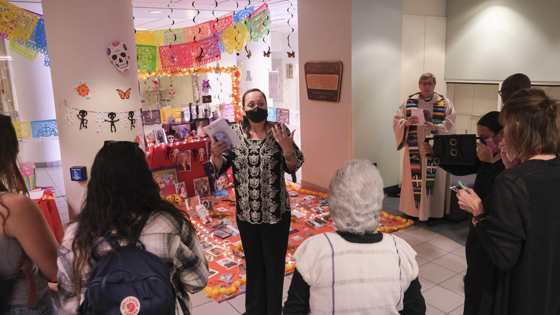 Lydia Kennedy (center), senior director of the UArizona Health Sciences Office of Equity, Diversity and Inclusion, speaks to about 75 attendees at the annual Dia de Los Muertos blessing ceremony in the Health Sciences Library. The altar behind her is filled with photos and remembrences from Health Sciences faculty, staff and students.