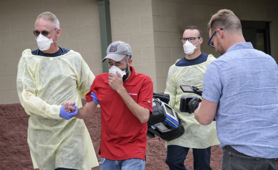 The Mel and Enid Zuckerman College of Public Health worked with Tucson Fire Department and the Western Regional Public Health Training Center to produce a training video for first responders on COVID-19 emergency calls in early March. Erich Healy, right, films as Tucson Fire Department’s Chris LaFave, left, helps guide Jonathan Sexton, PhD, who is playing a possible COVID-19 patient in a training video, into an ambulance.