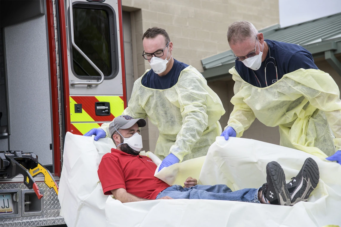 Firefighters Taylor Parrish and Chris LaFave wrap Jonathan Sexton, PhD, in a protective barrier to demonstrate how to prevent further spread of a virus during an ambulance trip to the hospital.