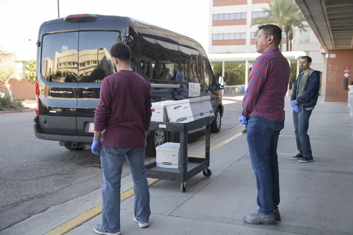 Lab Techs stand by before loading the kits into a Banner van as local media prepares to film.