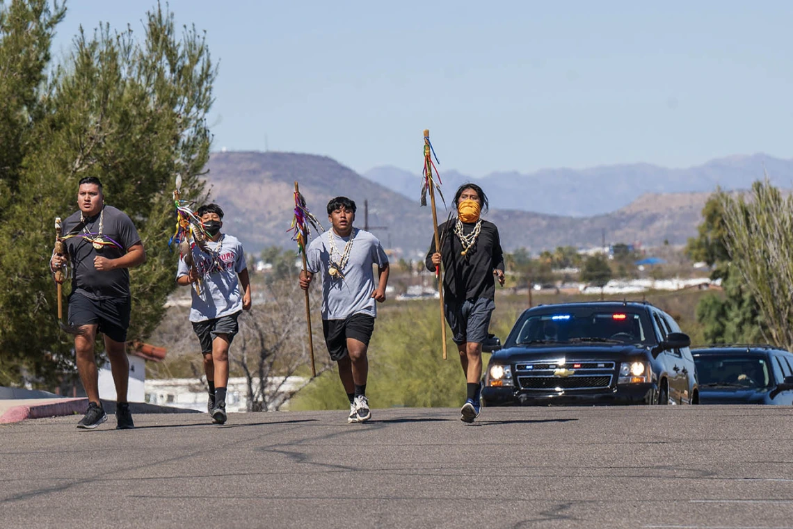 Four cultural runners escort first lady Jill Biden's motorcade onto the Tohono O'odham Nation during a visit to the San Xavier Health Center in the San Xavier District of the Tohono O'odham Nation March 8, 2022.