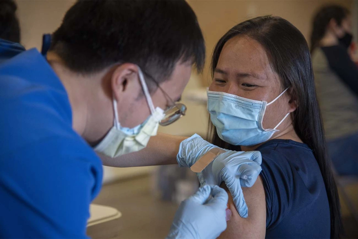 Alvin Wong, DO, a clinical associate professor with the College of Medicine – Phoenix, administers a COVID-19 vaccine to a patient at the community center in Aguila, Arizona, a rural agricultural community west of Phoenix in Maricopa County. 