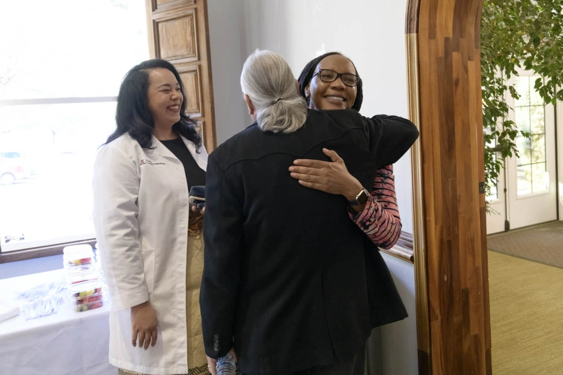 Primary Care Physician scholarship recipient Kaloni Philipp smiles as Dr. Carlos Gonzales congratulates scholarship recipient Beverley Trutter. 