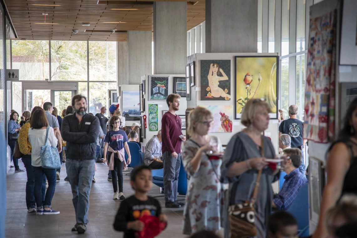 Attendees mingle in the Bioscience Research Laboratories lobby during the 10th annual “On Our Own Time” art exhibit, featuring art made by University of Arizona employees and their immediate family members.