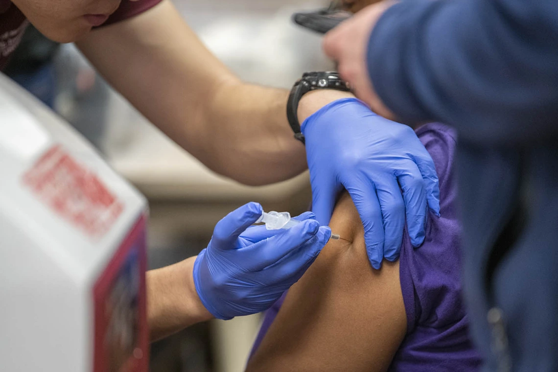 A Street Medicine Phoenix student volunteer administers the flu vaccine to a patient.