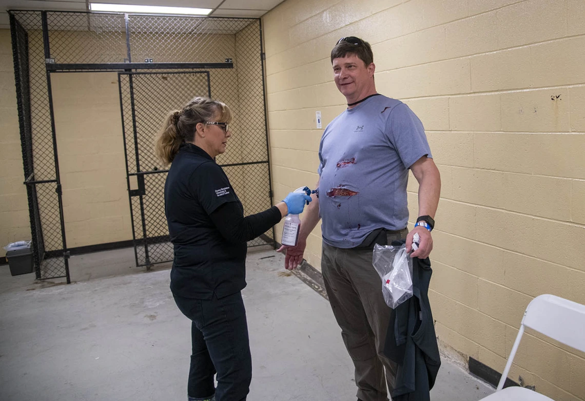 Peter Williams, a TPD volunteer playing an airplane passenger with wounds on his stomach, is on the receiving end of an air brush wielded by Deana Ann Smith, BS, BSN, RN, healthcare simulation educator for ASTEC.