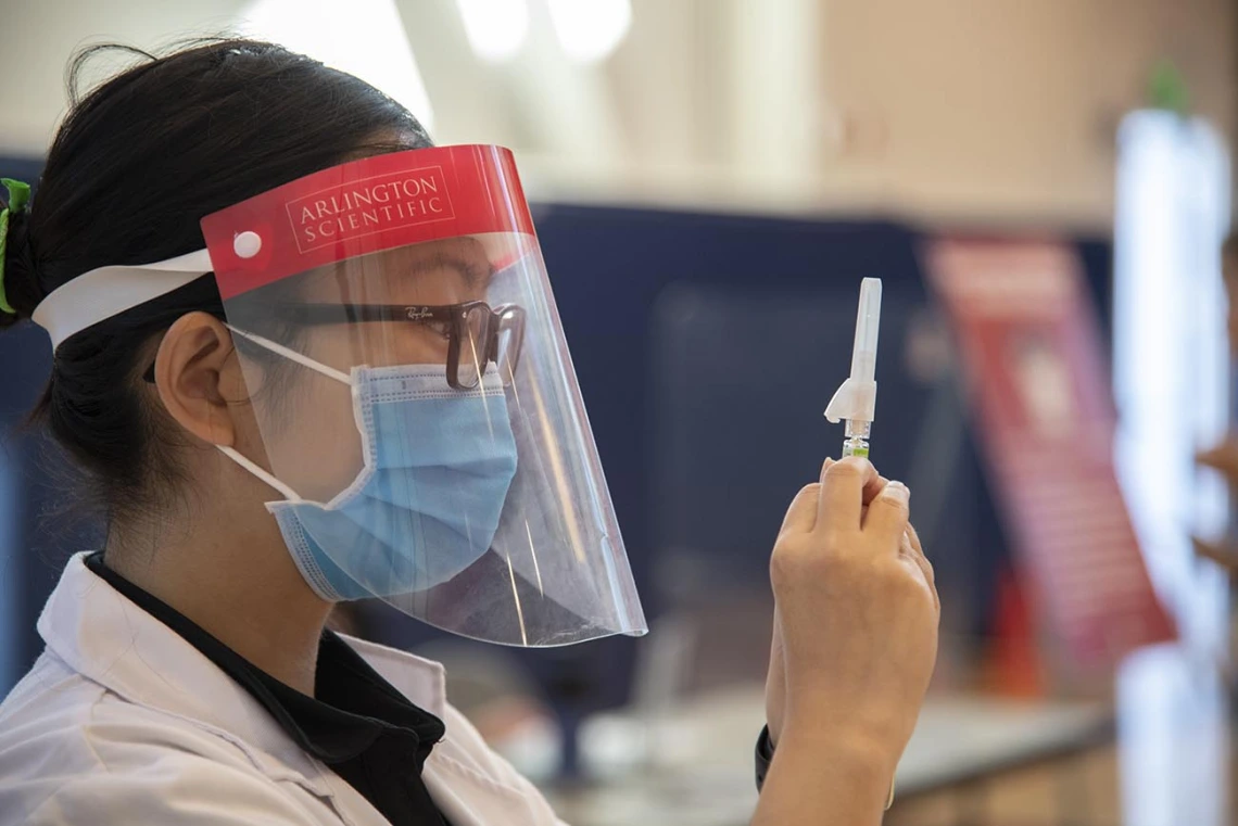 Fourth-year College of Pharmacy student Lisa Le expels air bubbles out of a flu vaccine before administering it to a fellow student as part of a student flu shot clinic in October.