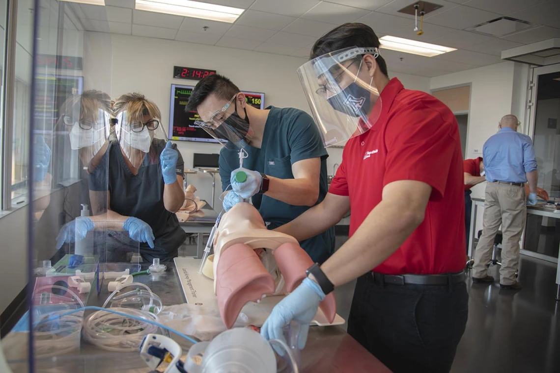 Second-year College of Medicine – Tucson students Paul Nguyen, left, and Arturo Hernandez practice intubation in the ASTEC lab Nov. 18. Instructor Deana Smith, BS, BSN, RN, is an ASTEC simulation education specialist.