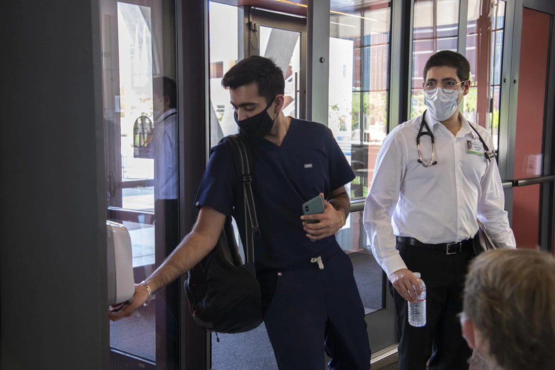 First year College of Medicine – Tucson student Yasi Suri, left, uses hand sanitizer before he and fellow first year student Jonathan Yasmeh head to a class in the Health Science Innovation Building.