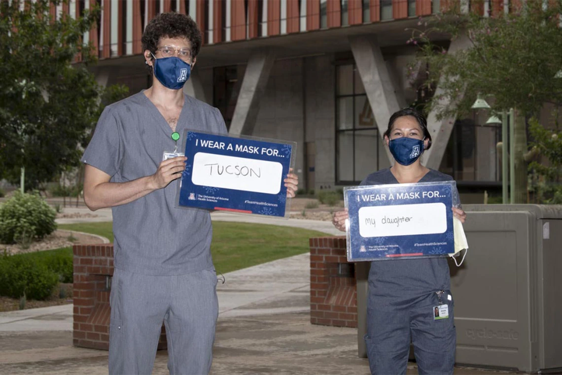 Third-year College of Medicine – Tucson students Asha Esprit and Brianna Dolana stand outside of the Health Sciences Innovation Building in Tucson. Esprit wears a mask for Tucson and Dolana wears a mask for her daughter. 