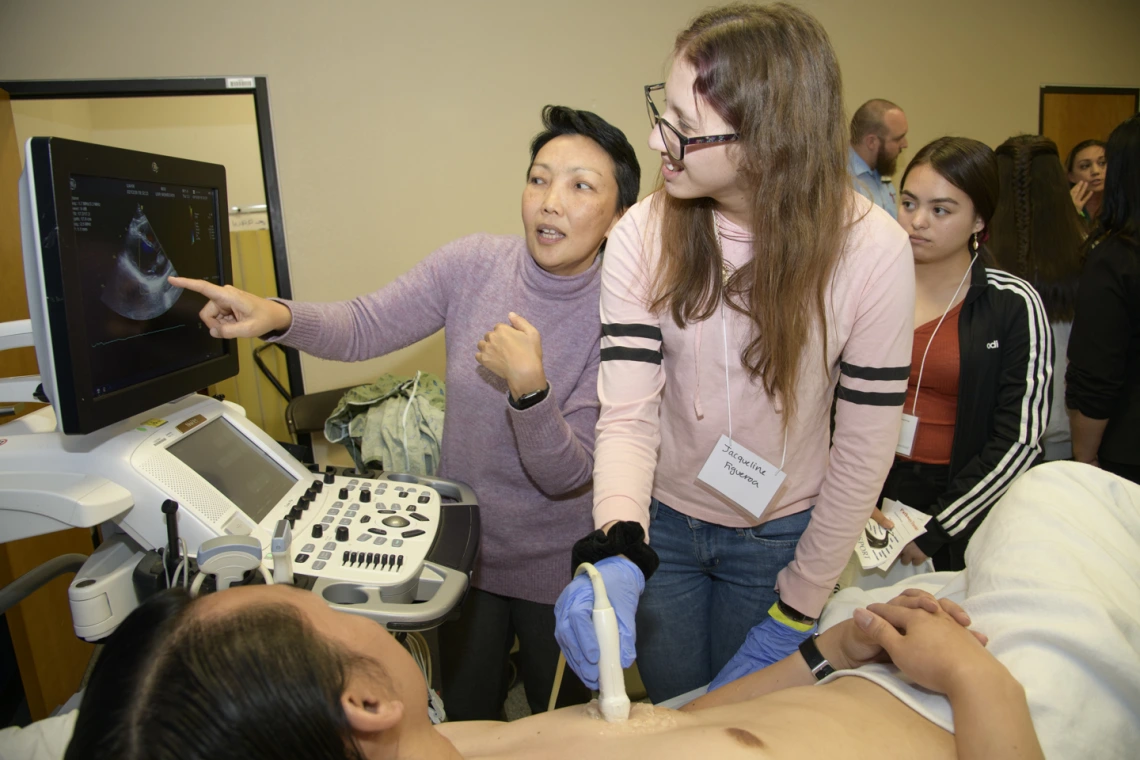 A high school student practices performing an ultrasound on a human heart.