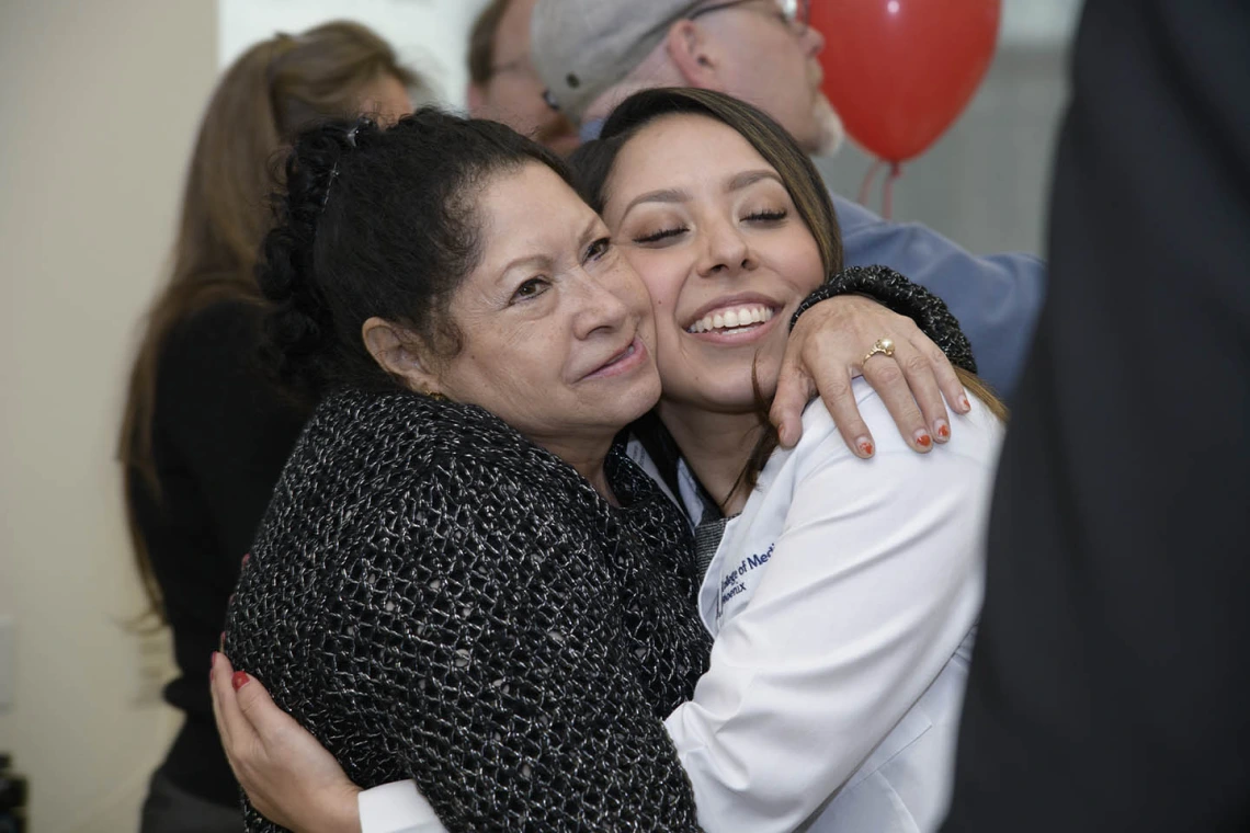 A family member congratulates Primary Care Physician scholarship recipient Abigail Solorio with a hug.