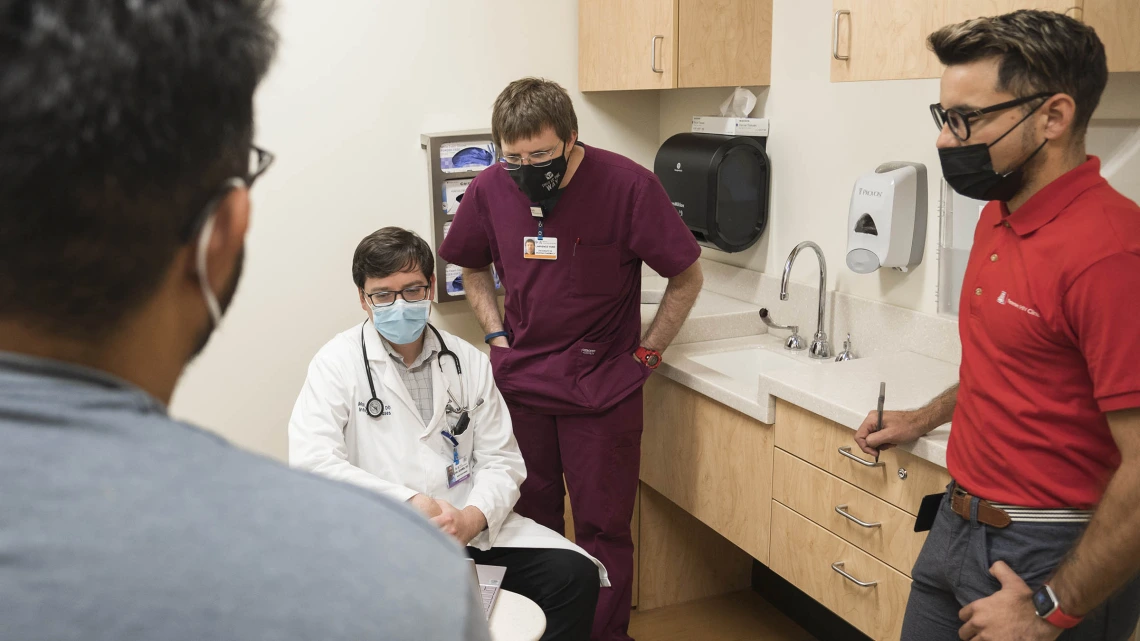 (From right) Cesar Egurrola, lead clinical coordinator and case manager; Larry York, PharmD, BCIDP, BCPS, AAHIVP, clinical pharmacist, infectious diseases and HIV/AIDS; and Matthew Adams, DO, speak with a visitor at the Petersen Clinic. 