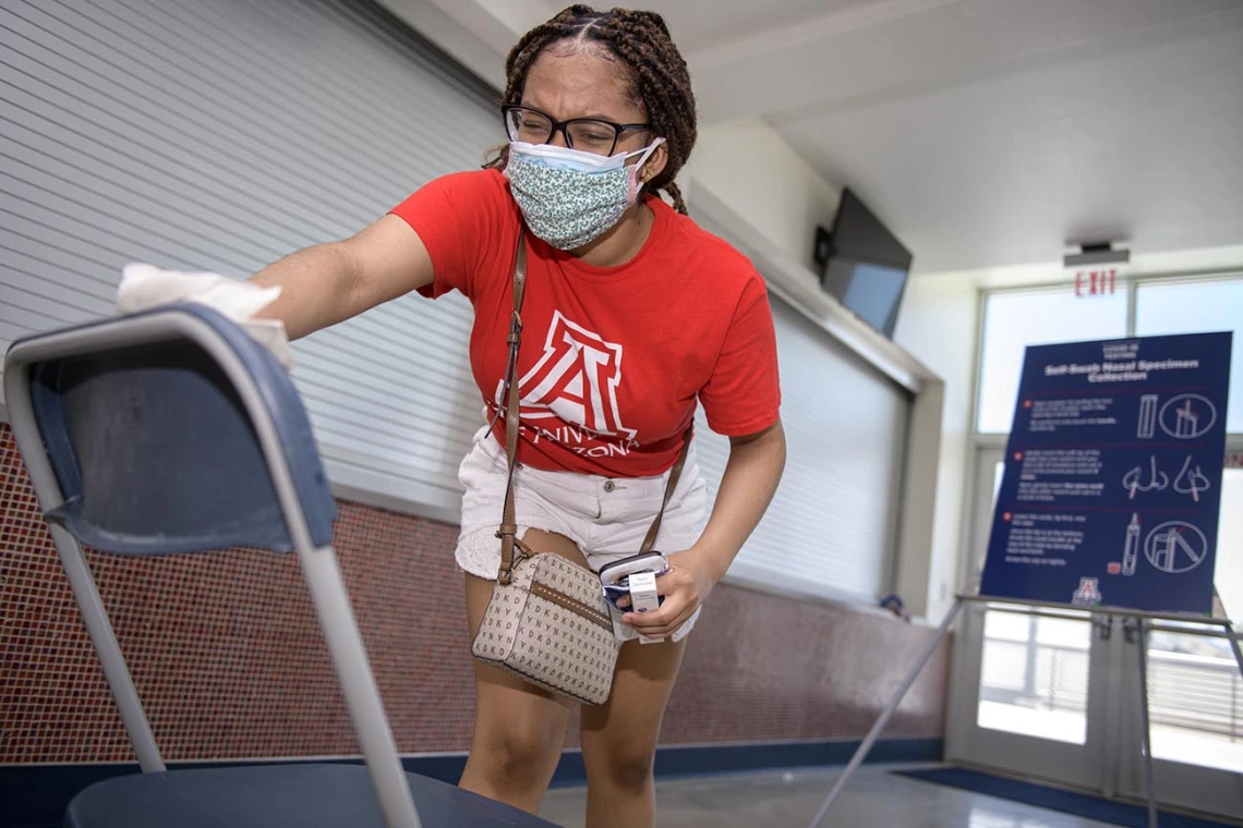 A student sanitizes her seat after completing a self-administered nasal swab antigen test for COVID-19 at McKale Center in Tucson. 