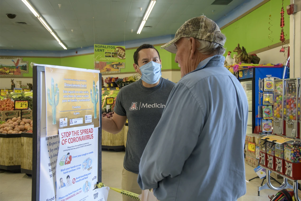 Ricardo Reyes, a College of Medicine – Tucson student, speaks with a customer at a Food City grocery store in Tucson about the social distancing campaign he and his classmates have created to inform the Spanish-speaking community. 