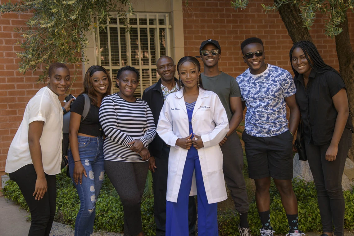 Judy Mburu pauses for a photo with family and friends after receiving her white coat during the R. Ken Coit College of Pharmacy class of 2023 white coat ceremony.