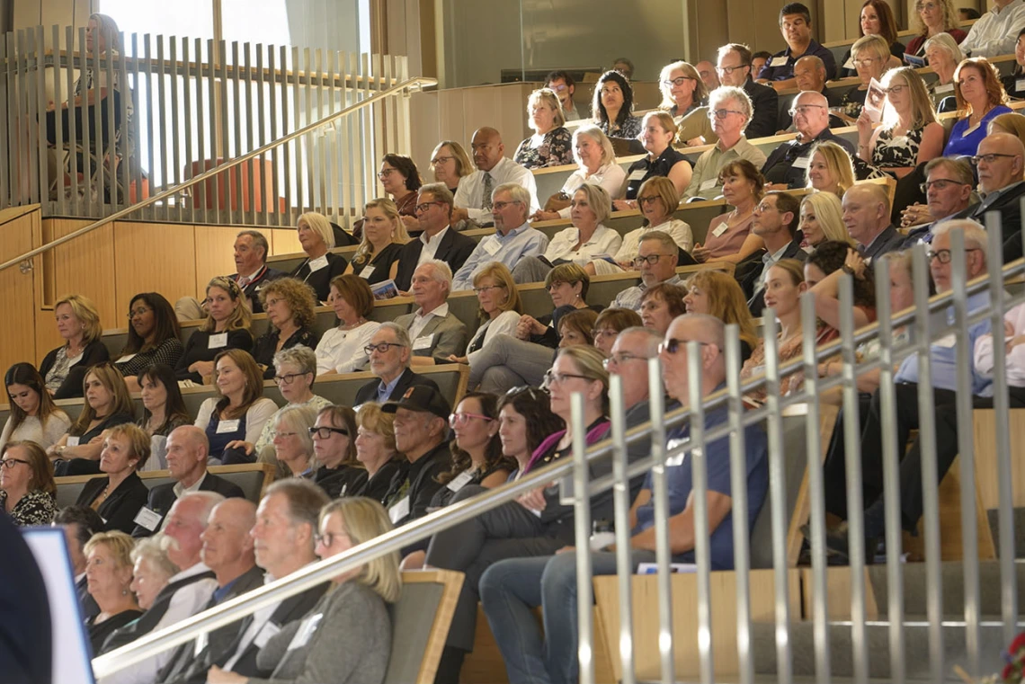 Hundreds of people sit in stadium-style seats during a memorial service for Mel Zuckerman.