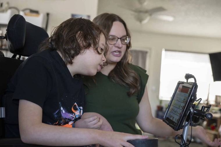 Mother and son in wheelchair looking at screen communication device