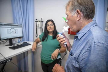 Research Technician Aida Hawatmeh (left) coaches a standardized patient through inspiratory muscle training. 