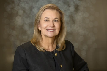 Woman with shoulder-length blonde hair wearing a black suit jacket.