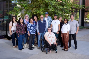 A group of 12 men and women pose for a photo in an outdoor setting. 