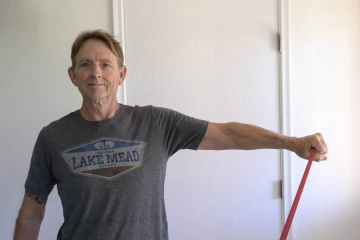 A person raises their arm to the side while using a resistance band for exercising.