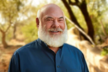 Portrait of Dr Andrew Weil, wearing a blue shirt in an outdoor setting