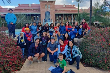 Fifth- and sixth-graders pose for a group photo with a few college students and teachers in front of Old Main’s fountain. 