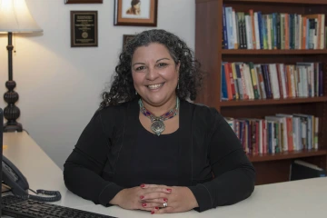 Portrait of Noshene Ranjbar, MD, sitting at a desk with a bookshelf behind her. 