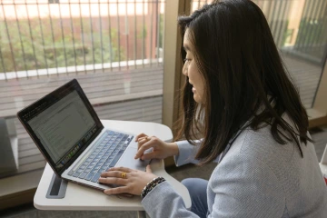 A doctoral student works on a laptop in a study area inside the UArizona Health Sciences Innovation Building. 