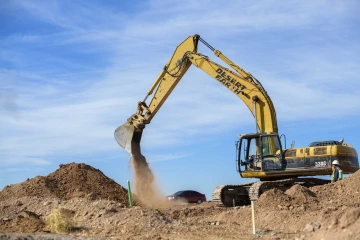 An excavator dumps dirt at a construction site