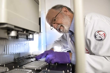 John Galgiani in a lab coat and gloves working in a laboratory.