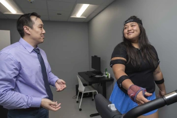 Jonathan Lee-Confer chats with a test subject fitted with sensors as she walks on a treadmill.