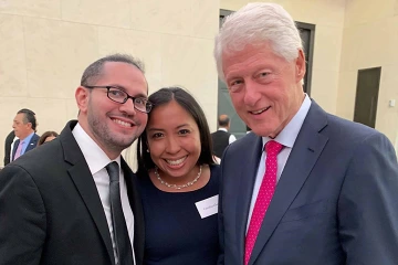 Ricardo Correa stands next to a woman and former President Bill Clinton. 