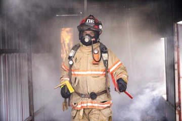 A firefighter walks away from smoke inside a structure