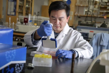 A researcher in a lab coat holding a multichannel pipette