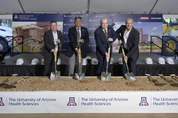 Four people with shovels in a box of dirt at a building groundbreaking ceremony for the Center for Advanced Molecular and Immunological Therapies