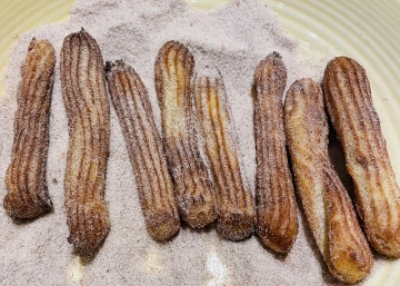 Churros dusted with cinnamon sugar on a plate