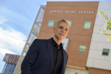 Researcher Hesham Sadek poses for a photo outside with the Sarver Heart Center in the background.