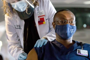 Christian Bime, MD, associate professor in critical care medicine and a pulmonary researcher at the UArizona College of Medicine – Tucson, was one of the first physicians at the college to be vaccinated against COVID-19. Originally from Cameroon, he said acquaintances in Africa saw the image, as well as news video of him touting the vaccine, and it helped dispel their hesitancy to get vaccinated themselves. (Courtesy of Arizona Daily Star, Rebecca Sasnett)