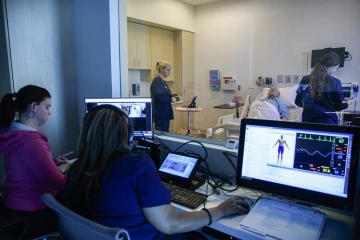 Nursing students observe one another during a simulated learning exercise.