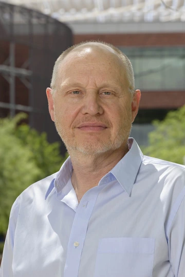 Middle-aged man wearing a light blue shirt while standing outside.