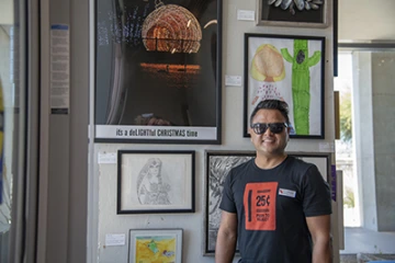 Shailender Chauhan stands next to his art “it’s a deLIGHTful CHRISTMAS time” Chauhan works for Cellular & Molecular Medicine