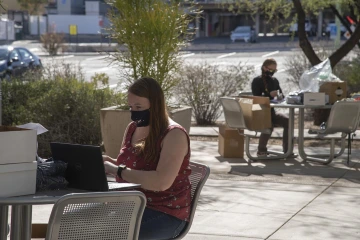 Public health doctoral student and epidemiologist Erika Austhof, MPH, foreground, helps other grad students assemble thank-you packets for study participants in a physically distanced setting outside Drachman Hall.